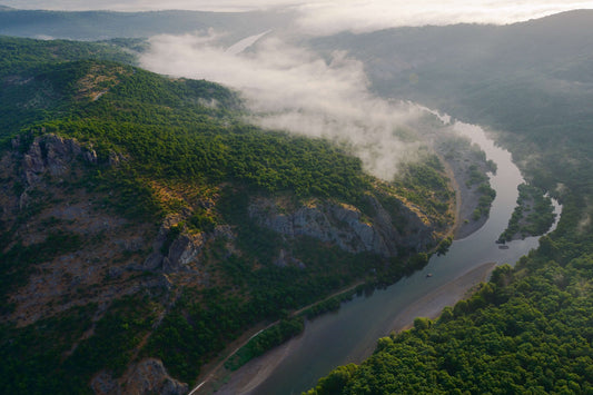 Aufnahme aus der Luft: eine weite, grüne, hügelige Landschaft, durchzogen von einem gewundenen Fluss.