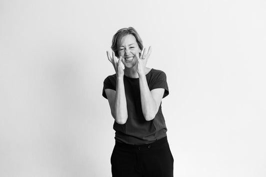 Ein schwarz-weiß Bild von Wildling Gründerin und Geschäftsführerin Anna Yona. Sie ist vom Kopf bis zur Hüfte im Bild, trägt ein dunkles T-Shirt und eine dunkle Hose, Gestik und Mimik signalisieren Aufregung.