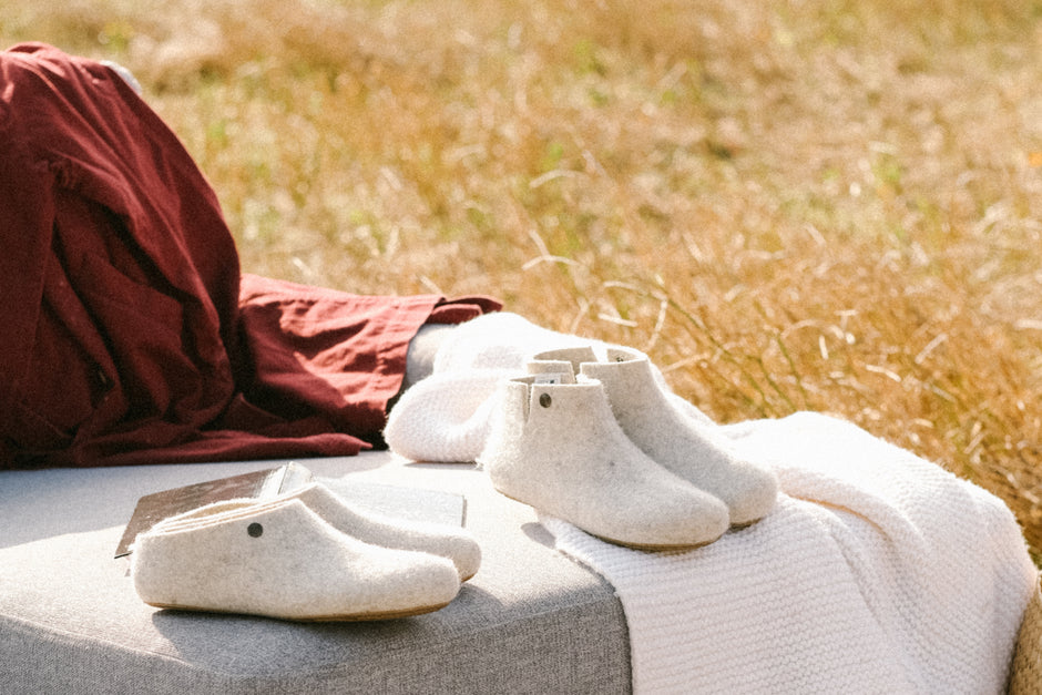 Die Hausschuhe Lotus und Nelus auf einem Sofa, im Hintergrund ein Kornfeld.